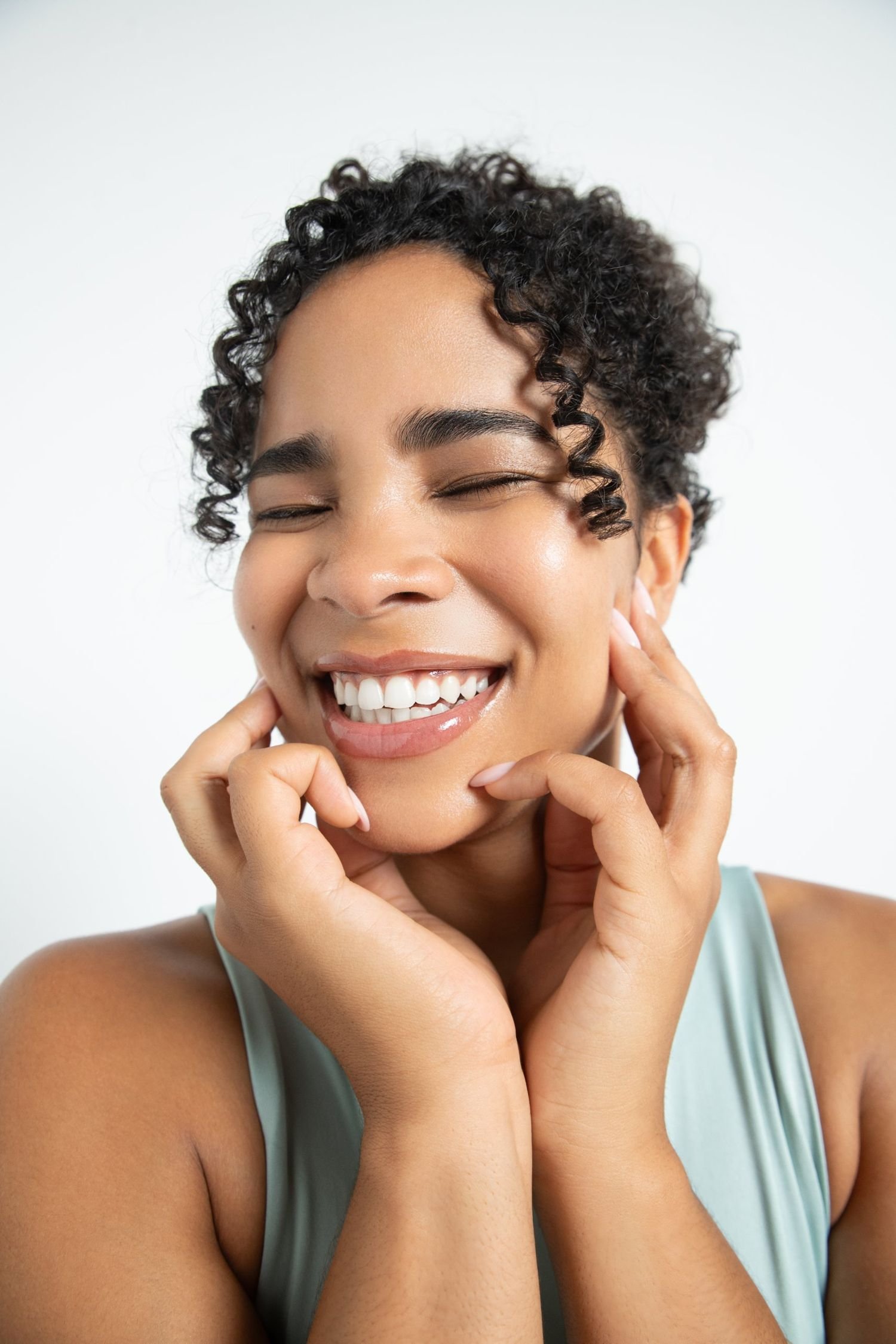 Cetaphil campaign: Smiling model with curly hair, hands framing her face, mint top